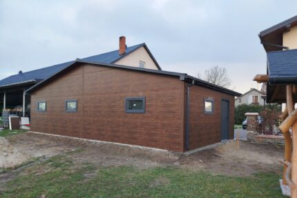 Garaż z płyty warstwowej 10x6 -Dach dwuspadowy, Ocieplany, Kolor drewnopodobny orzech, Brama Segmentowa, Drzwi wejściowe