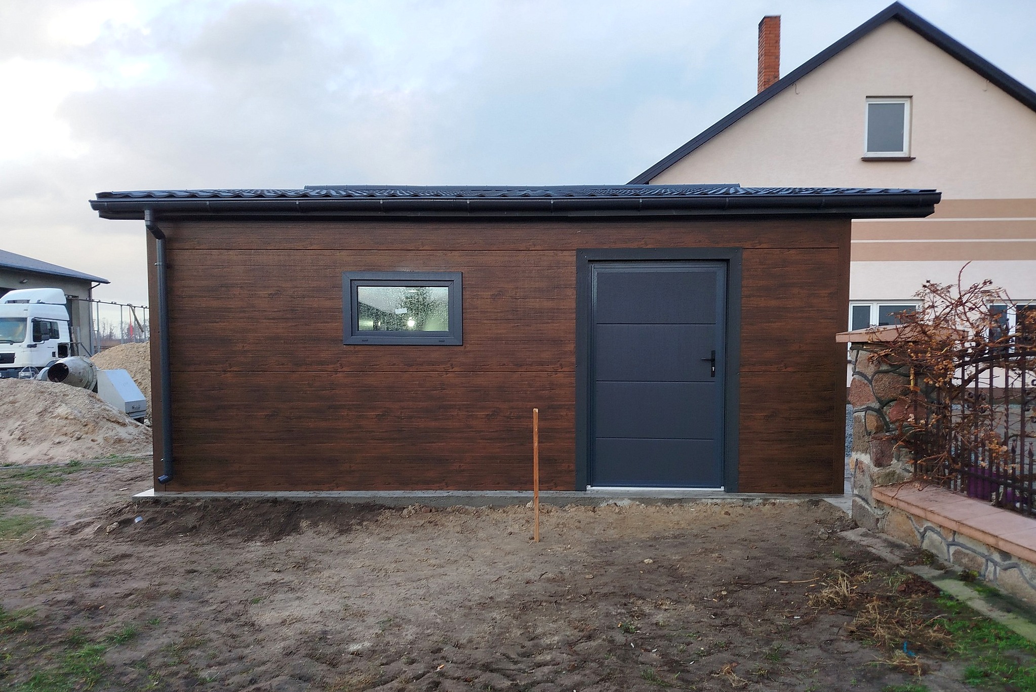 Garaż z płyty warstwowej 10x6 -Dach dwuspadowy, Ocieplany, Kolor drewnopodobny orzech, Brama Segmentowa, Drzwi wejściowe Garaż z płyty warstwowej 10x6 -Dach dwuspadowy, Ocieplany, Kolor drewnopodobny orzech, Brama Segmentowa, Drzwi wejściowe