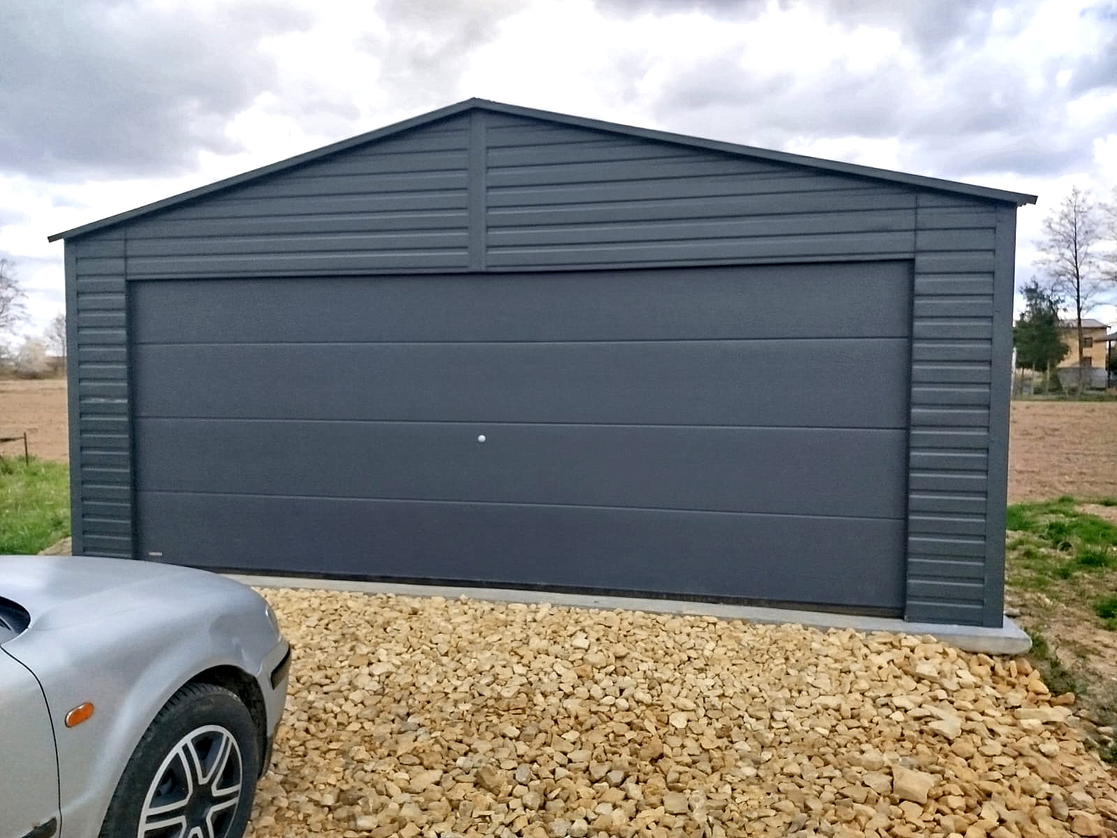 Garaż blaszany 6x6 - Dwustanowiskowy, Dach dwuspadowy, Kolor antracyt, Brama segmentowa Garaż blaszany 6x6 - Dwustanowiskowy, Dach dwuspadowy, Kolor antracyt, Brama segmentowa