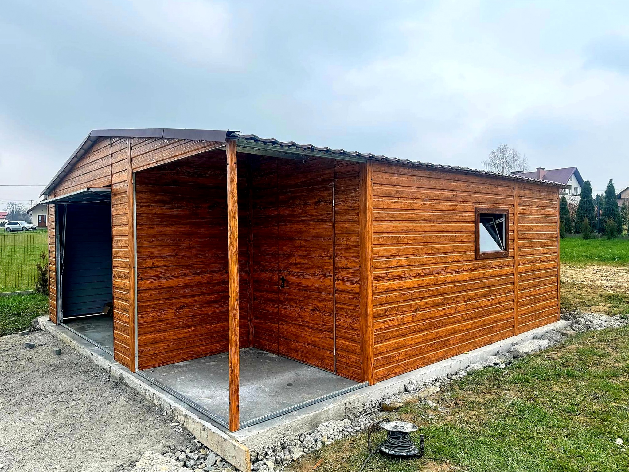 Garaż blaszany 6x6 - Dach dwuspadowy, Wiata, Kolor drewnopodobny Złoty dąb, Brama uchylna Garaż blaszany 6x6 - Dach dwuspadowy, Wiata, Kolor drewnopodobny Złoty dąb, Brama uchylna