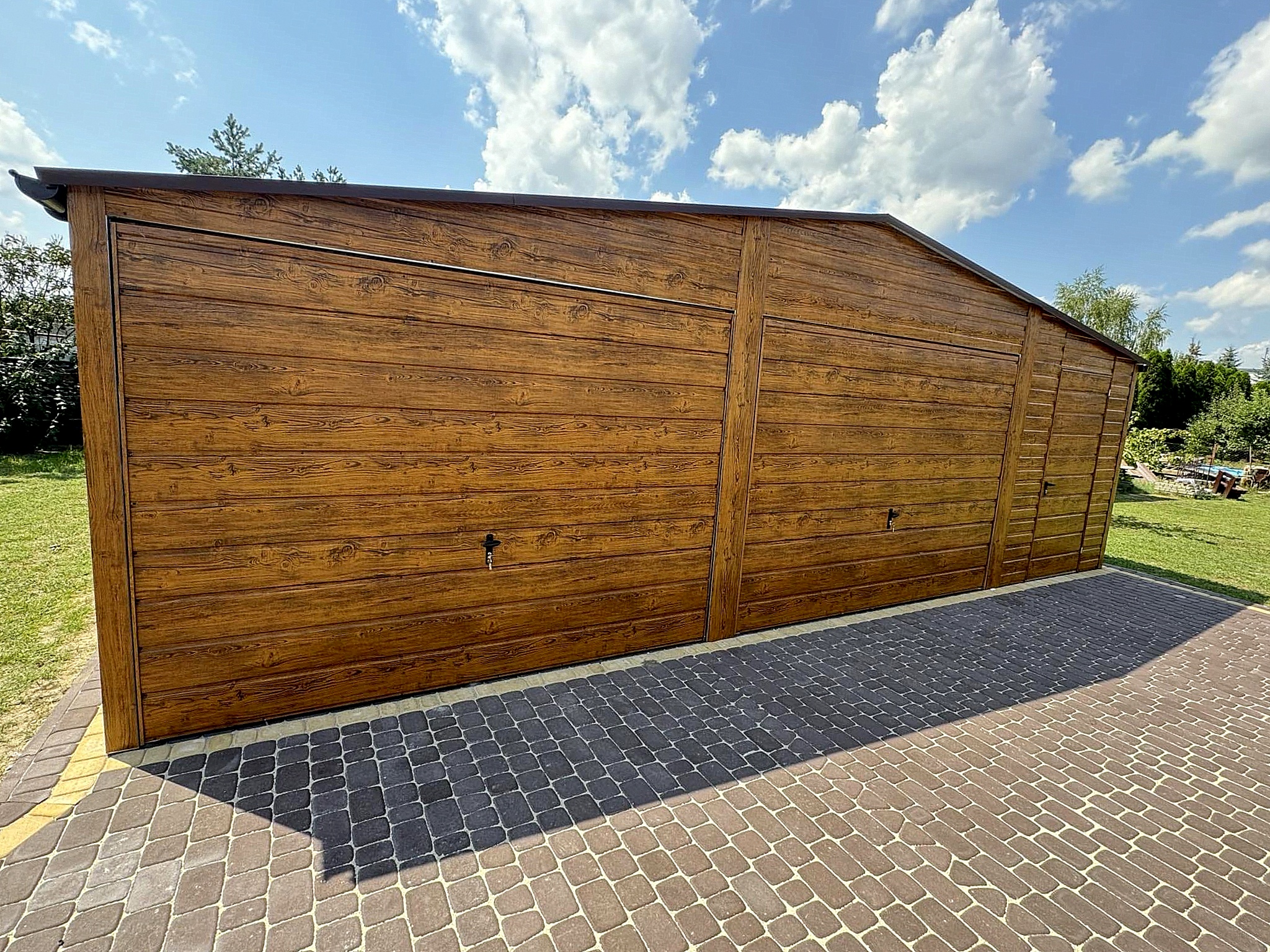 Garaż blaszany 8x6 - Dwustanowiskowy, Dach dwuspadowy, Kolor drewnopodobny złoty dąb, Bramy uchylne, Drzwi wejściowe Garaż blaszany 8x6 - Dwustanowiskowy, Dach dwuspadowy, Kolor drewnopodobny złoty dąb, Bramy uchylne, Drzwi wejściowe